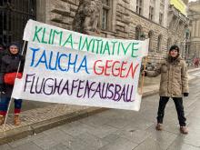 Foto von 2 Menschen mit einem Transparent mit der Aufschrift Klima-Initiative Taucha gegen Flughafenausbau