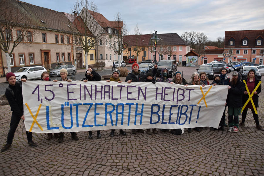Menschen auf dem Marktplatz mit einem Transparent mit der Aufschrift: 1,5° einhalten heißt: Lützerath bleibt!